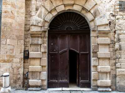 Ci spostiamo infine davanti all�ingresso costituito da un ampio portone in legno circoscritto in un portale ad arco centinato con paraste e doppia fascia di bugne